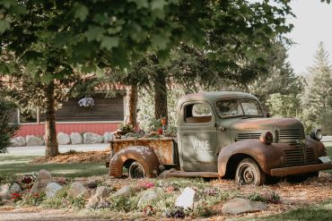 Rustic vintage truck parked outdoors with flowers.