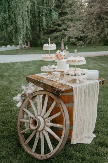 Rustic dessert table with cupcakes and cake outdoors.