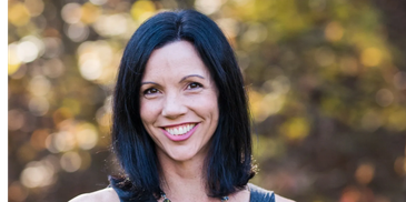 Smiling woman with dark hair outdoors.