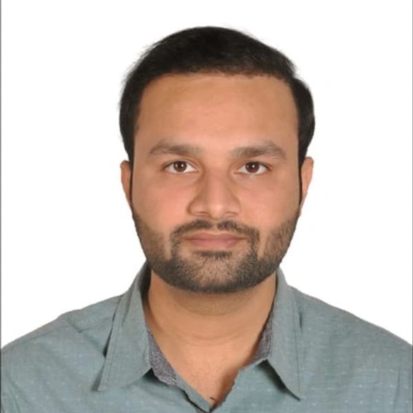 Portrait of a man with a beard wearing a green shirt against a white background.