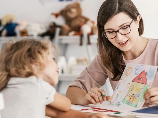 an adult woman showing a house drawing to a kid