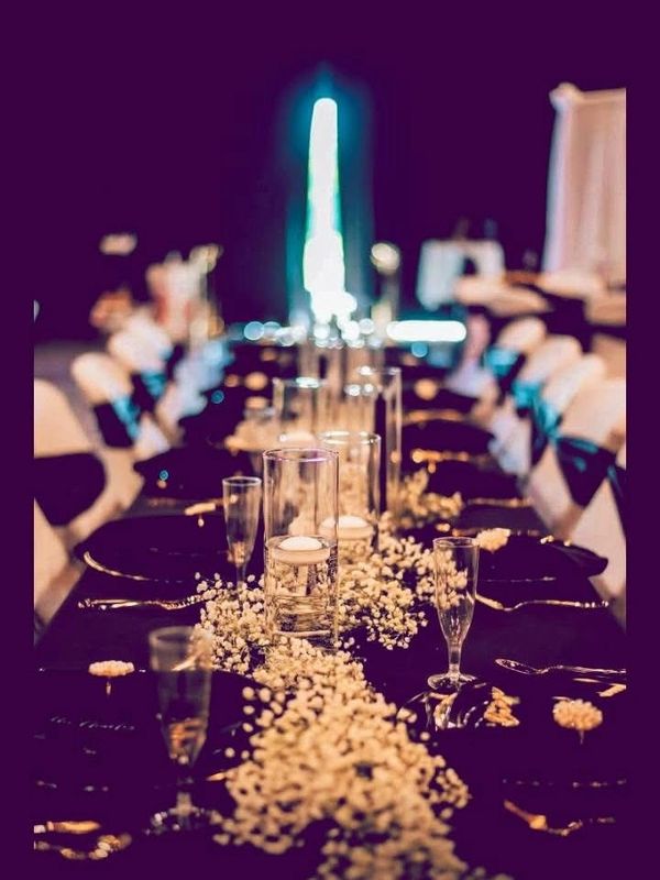 Elegant wedding table with black and white decor and floating candles.