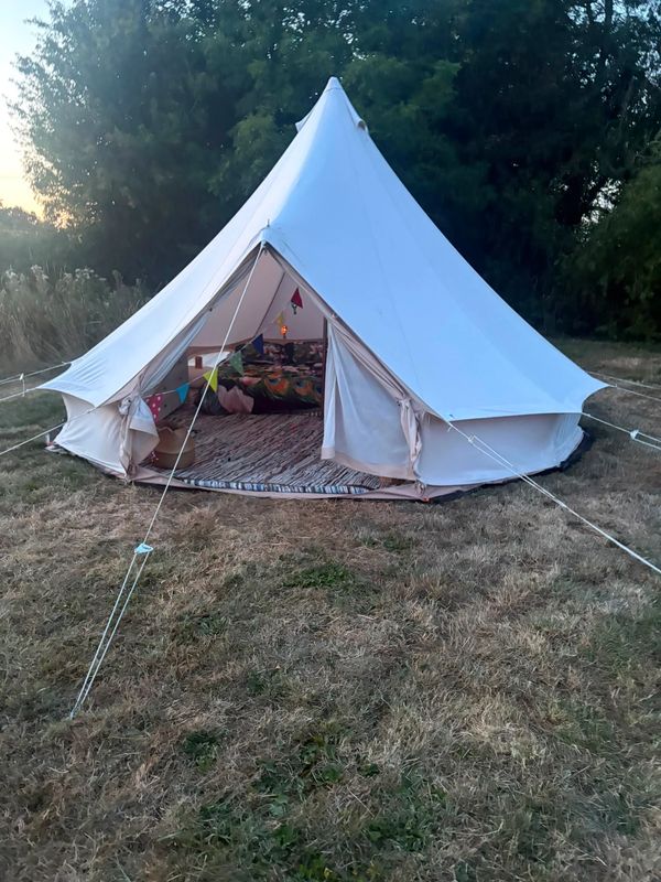 White camping tent set up in grassy field.