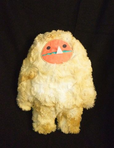 Yeti plushie with orange face and pocket mouth