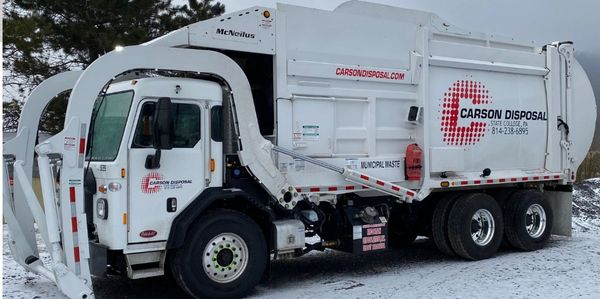 Garbage truck from Carson Disposal company on snowy ground.