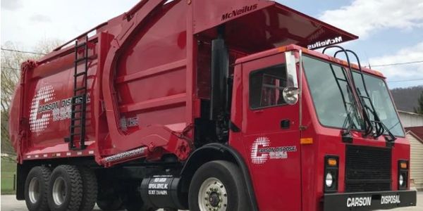 Red Carson Disposal garbage truck parked outdoors.