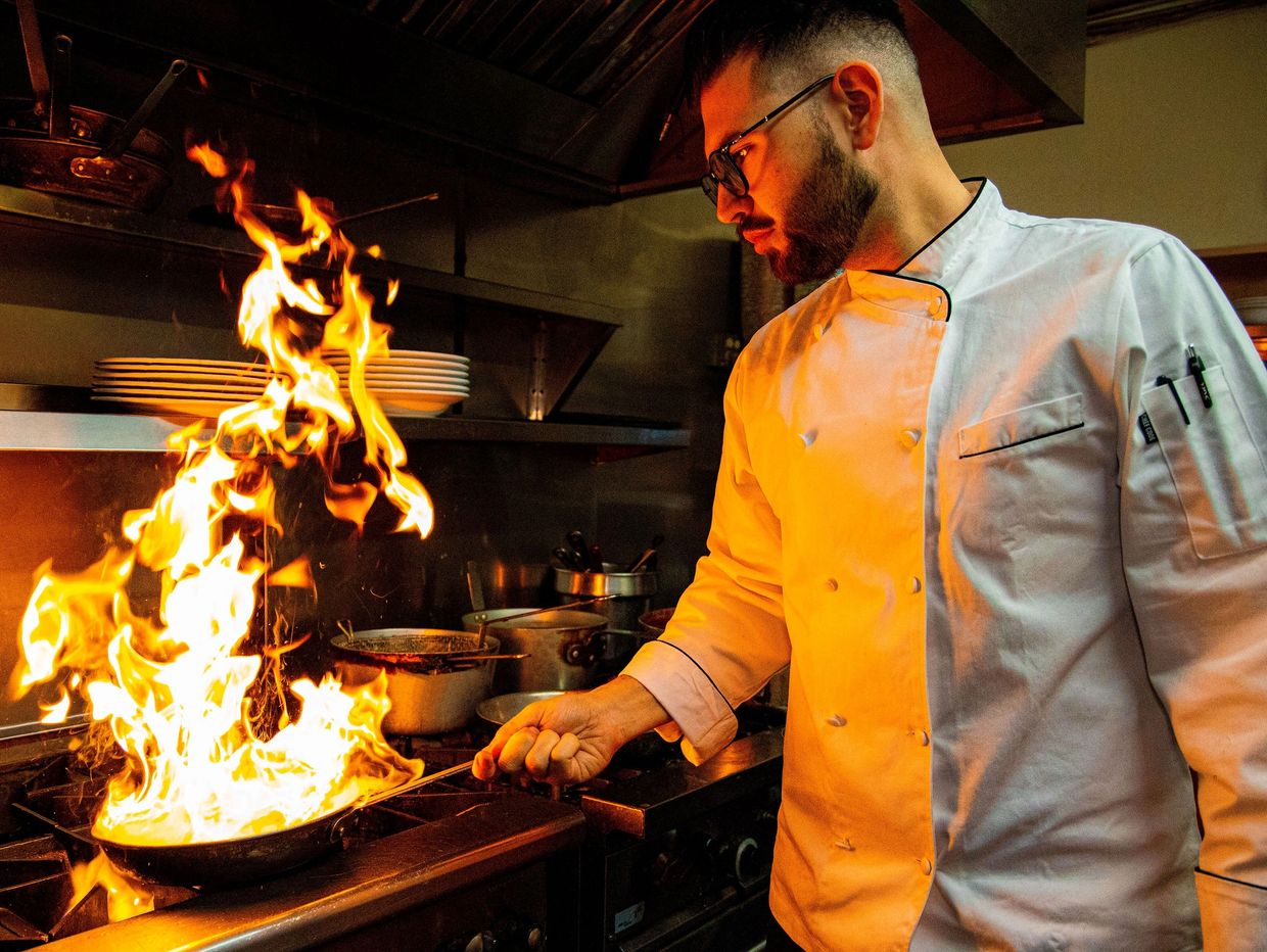 A chef frying food in a pan 