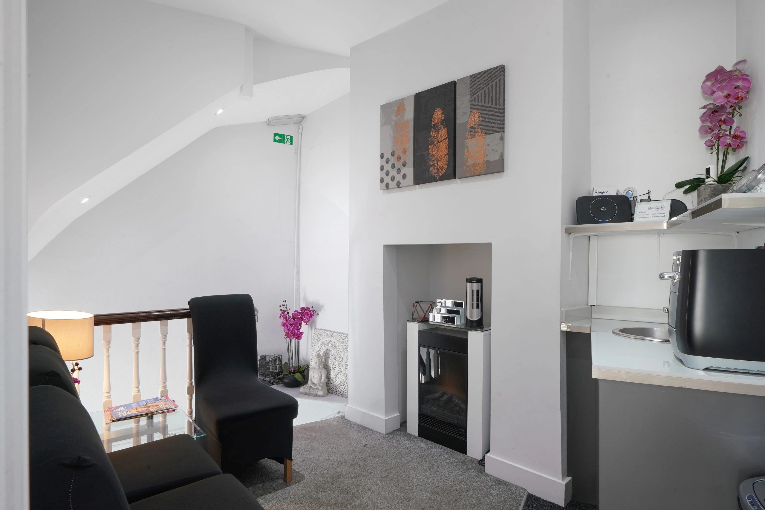 Cozy modern waiting area with black chairs, fireplace, and decorative orchids.