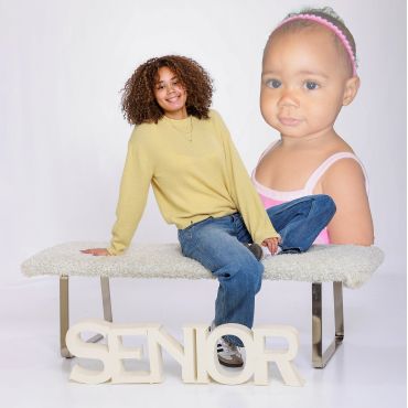 Young woman posing with a large baby photo and 'SENIOR' letters.
