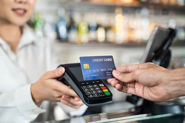 Person making a payment using a credit card and a card reader.