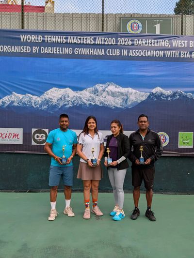 Four tennis players holding trophies on a court with a mountain backdrop.