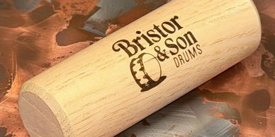 Close-up of a wooden drumstick with Bristor &amp; Son Drums logo.