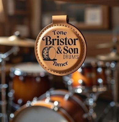 Leather tag with Bristor &amp; Son Drums logo in front of a drum set.