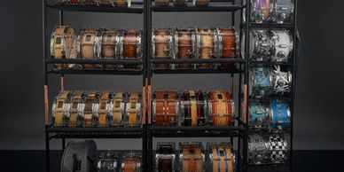 A collection of various snare drums displayed on shelves and racks.