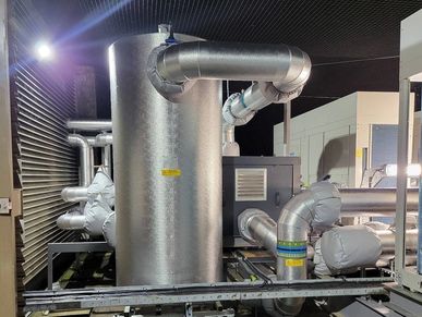 Industrial HVAC system with insulated pipes and metal structures at night.