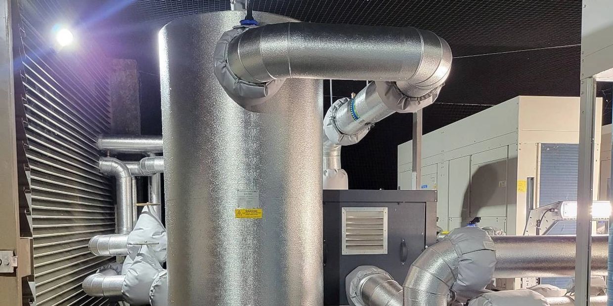 Industrial HVAC system with insulated pipes and metal structures at night.