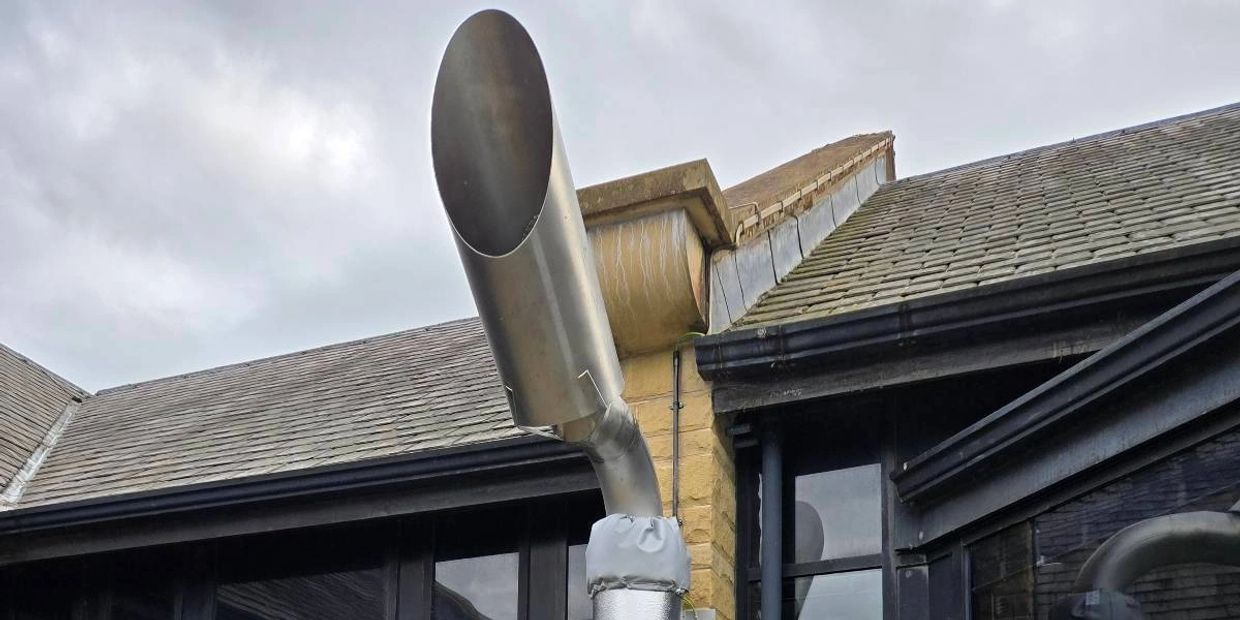 Metal ventilation pipe attached to a building exterior.