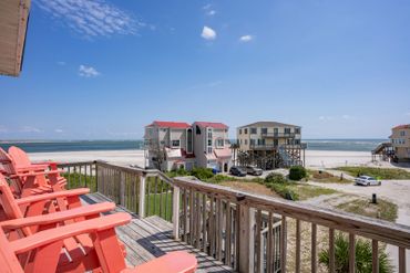 Colorful beach houses and red chairs overlooking the ocean on a sunny day.