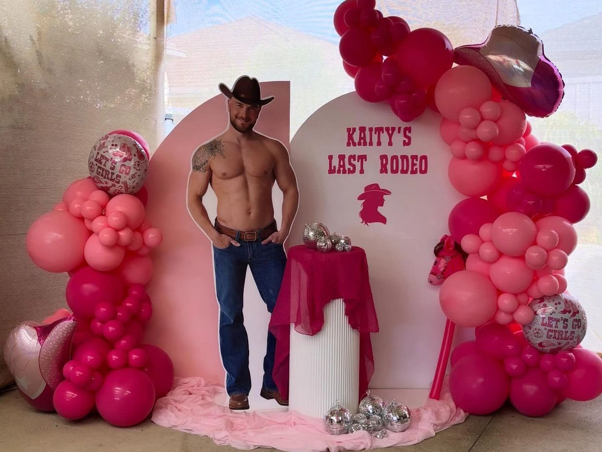 Pink rodeo-themed party setup with balloons and cowboy cutout.