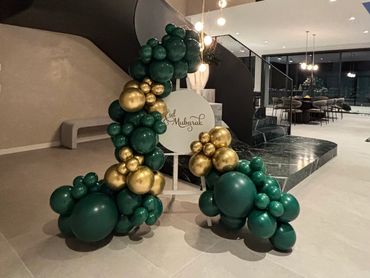 Green and gold balloon decoration with a Mubarak sign in a modern indoor setting.