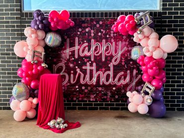 Vibrant birthday backdrop with balloons and disco balls.