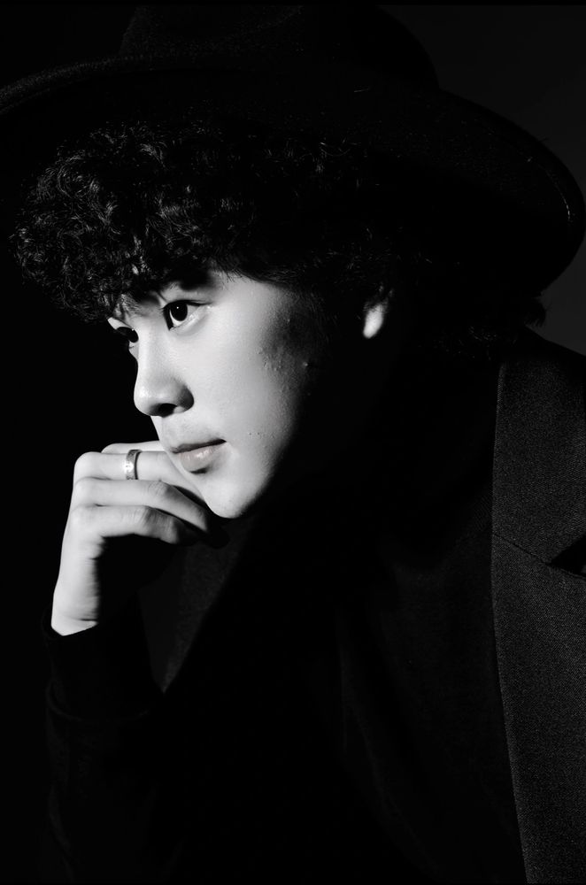 Black and white portrait of a thoughtful young man in a hat.