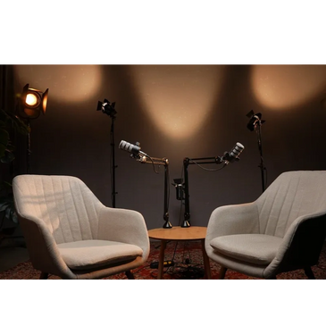 Two gray chairs with microphones set for a recorded conversation or podcast.