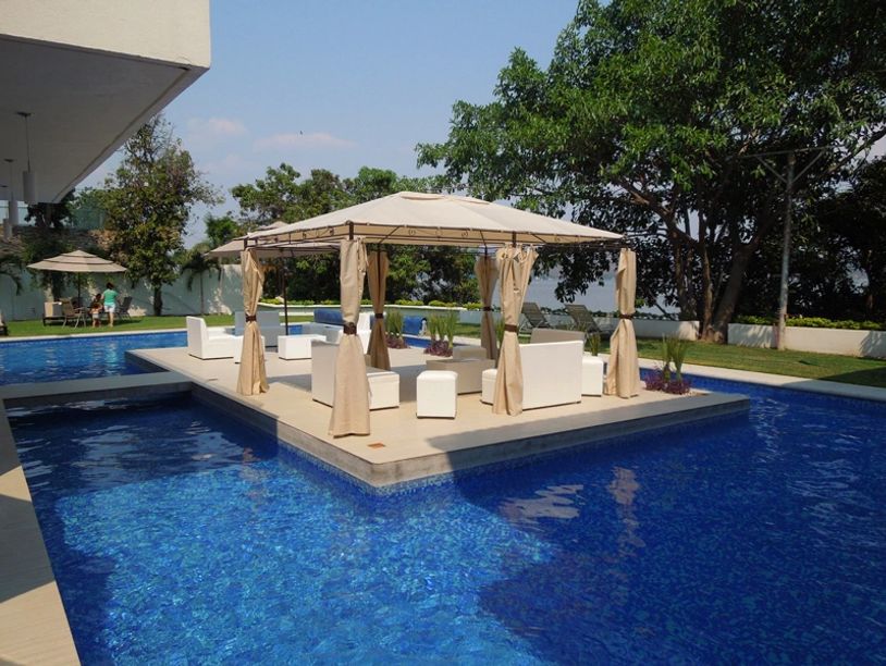 Zona de descanso con piscina y toldo en un jardín.