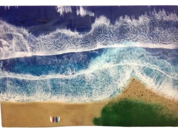 Aerial view of a beach with a small peninsula. Waves coming in. Surf boards on the sand. Pod of dolp