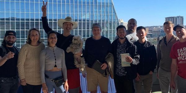 Group of people posing with books on tables and a city backdrop.