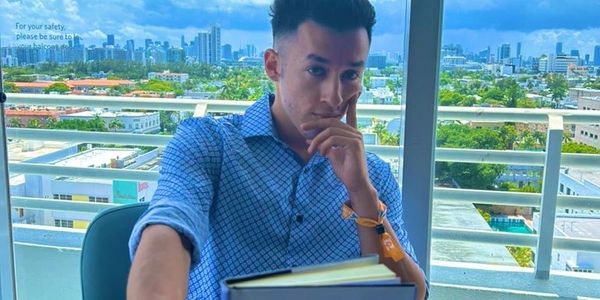 Man in blue shirt holding a business book with a cityscape background.