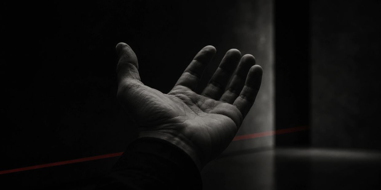 Mano extendida en un entorno oscuro y minimalista.