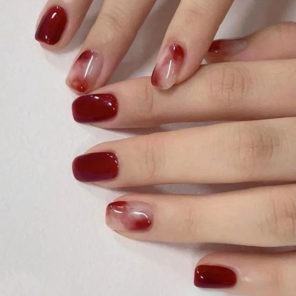 Manicure with dark red and translucent blood splatter nails.