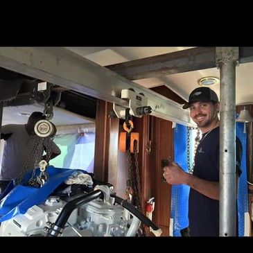 Man smiling and giving thumbs up while working on a boat engine.
