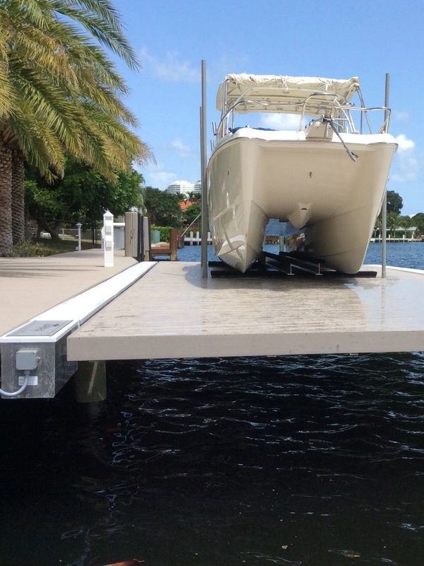 A boat docked on a lift platform by the water under a sunny sky.