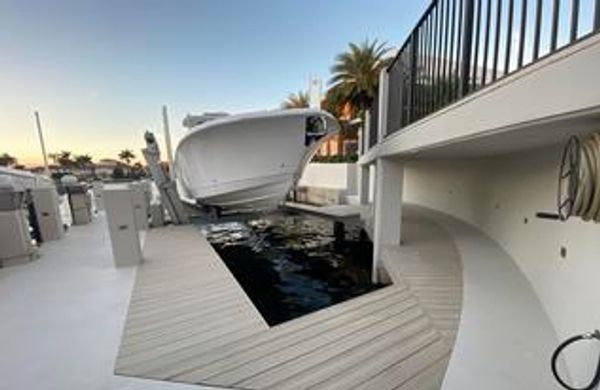 A boat docked in a modern, curved marina slip during sunset.