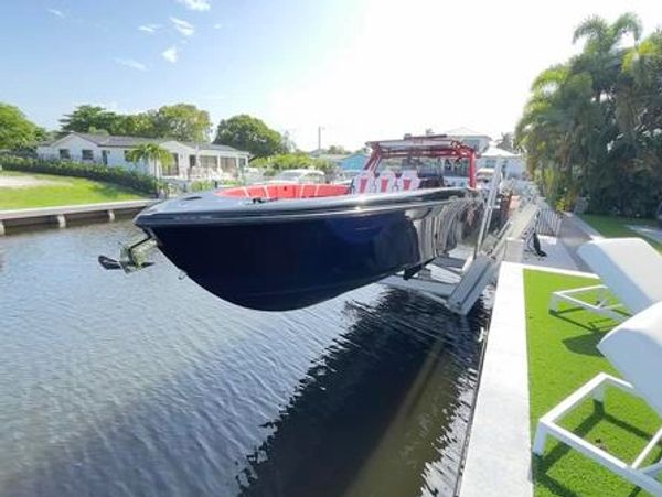 A sleek black boat lifted above canal water near a modern dock.