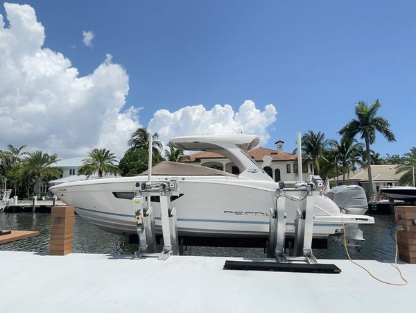 A white luxury boat docked on a lift with a clear blue sky.
