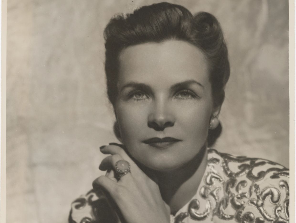 Black and white portrait of a woman with styled hair and patterned clothing.