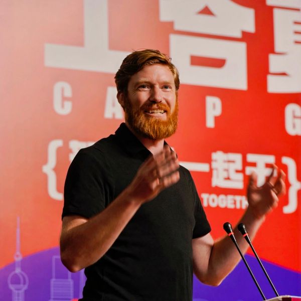 A man with a red beard speaking energetically at a podium.