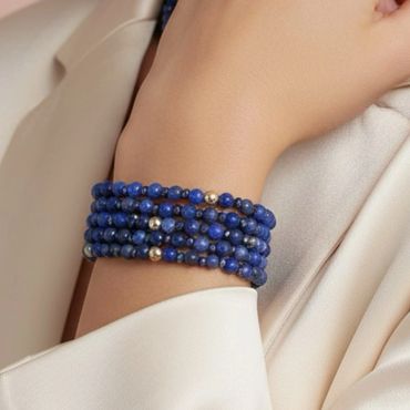 Elegant blue beaded bracelet with gold accents worn on wrist.