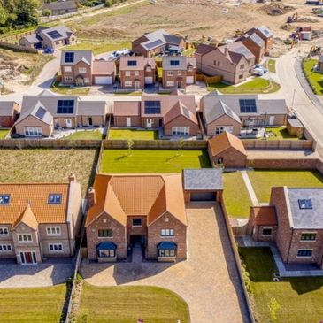 Aerial view of modern suburban homes with solar panels and well-maintained yards.