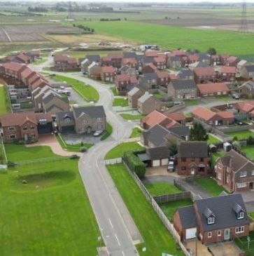 Aerial view of a suburban neighborhood with houses and green fields.