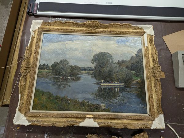 Framed painting of a riverside scene with boats and trees, showing some wear on the frame.