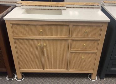 Wooden cabinet with brass handles and a white countertop.