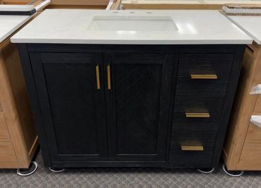 Modern black bathroom vanity with gold handles and white countertop.