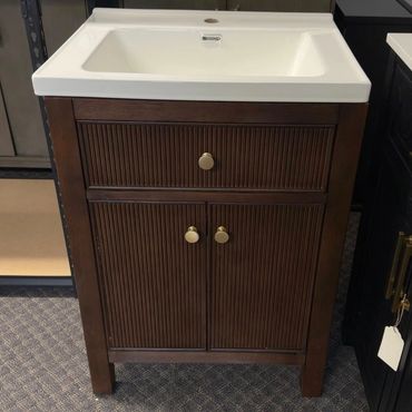Wooden bathroom vanity with white sink and brass handles.