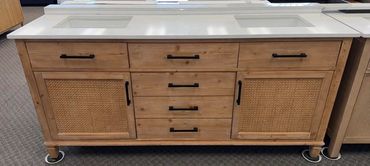 Wooden bathroom vanity with white countertop and dual sinks.