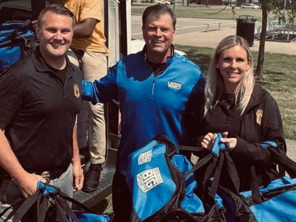 Photo of Detectives Michelle Day and Tim Bakula picking up  duffel bags for the City’s patrol cars