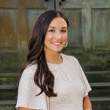 Smiling woman with long dark hair in a light dress.